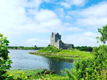 Scenic view of river by buildings against sky