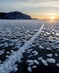 Surface level of frozen lake against sky during sunset