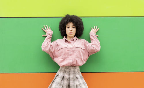 Curly hair woman leaning on colorful wall
