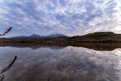 Scenic view of lake by mountains against sky