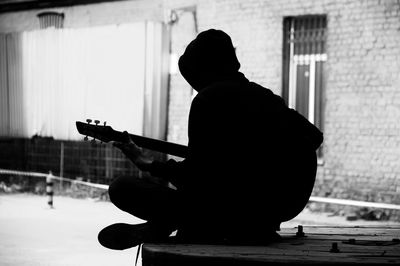 Silhouette teenage boy playing guitar