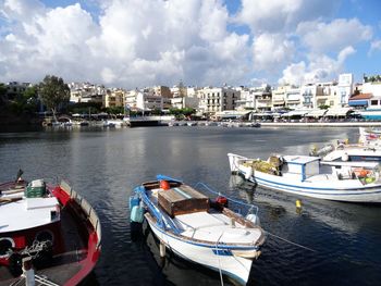 Boats moored at harbor in city against sky