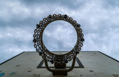 Directly below shot of basketball hoop against cloudy sky