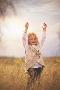 Smiling girl standing on field against sky