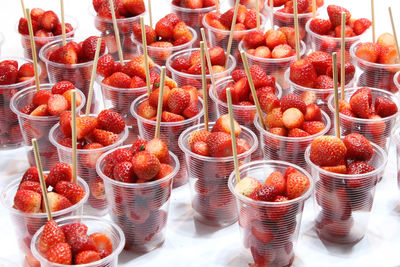 Fresh strawberry berries in transparent plastic glasses for sale on village marke
