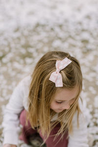 Preschool girl looking down at ground outside