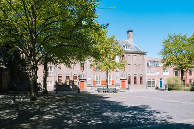 Street amidst trees and buildings against sky