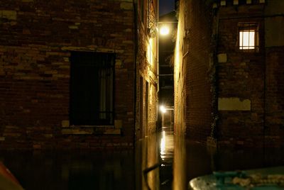 Illuminated alley amidst buildings at night