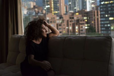 Thoughtful woman sitting on sofa in city