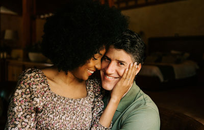 From above of loving black woman sitting on knees of man while embracing at home