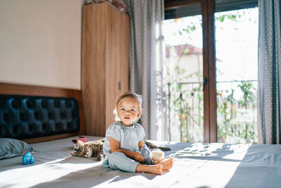 Portrait of boy sitting on bed at home