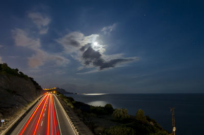 Panoramic view of road by sea against sky at night