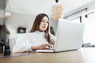 Young girl at home in front of the laptop doing her homework, distance learning