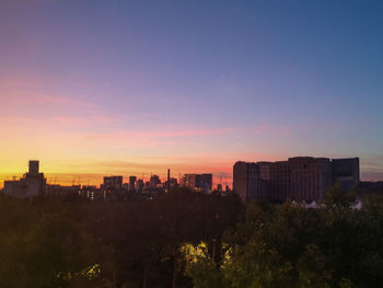 Buildings in city against sky during sunset