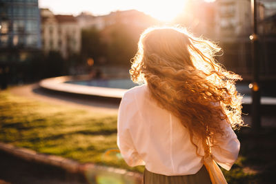 Rear view of woman standing in city during sunset