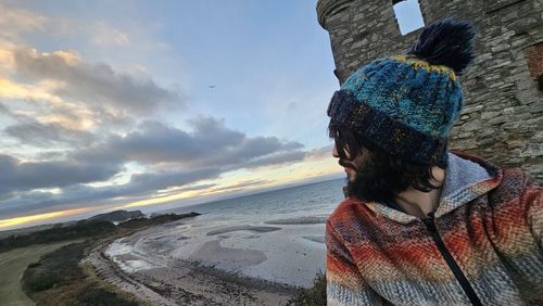 Rear view of woman standing against sky during sunset
