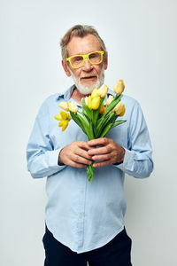 Portrait of senior man holding tulip against white background