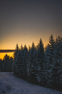 Snow covered land against sky during sunset