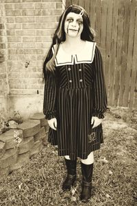 Portrait of young woman standing against wall