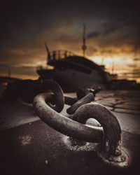 Close-up of rusty chain against sky in city during sunset