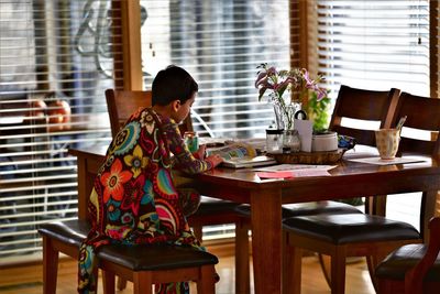 Full length of boy sitting on table at home