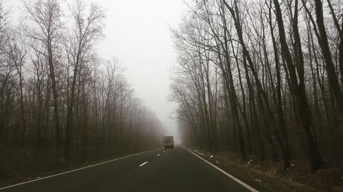 Road amidst trees in forest against sky