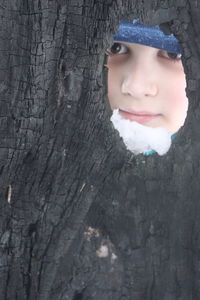 Close-up portrait of cute boy in tree trunk