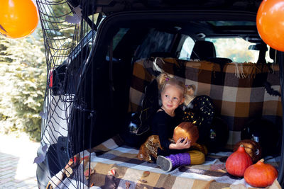 Cute little girl celebrating halloween in car trunk. stay home celebration. autumn holidays.