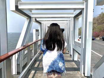 Rear view of woman walking on railing