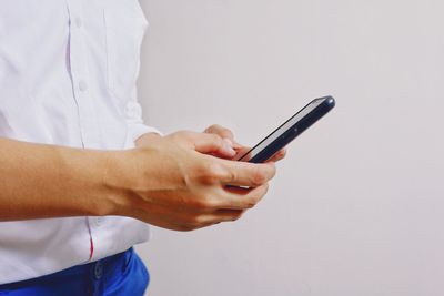 Midsection of man using smart phone against white background