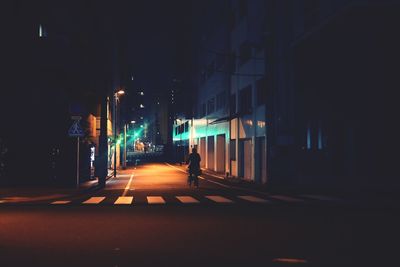 Illuminated street amidst buildings in city at night