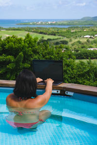 Rear view of woman looking at swimming pool against sky