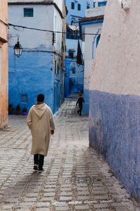 Rear view of man walking on cobblestone