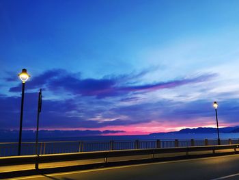 Street lights on bridge against sky at sunset