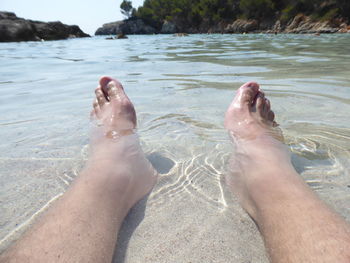 Low section of man relaxing at beach