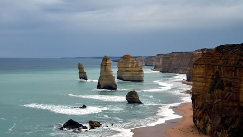 View of rocks on beach against cloudy sky