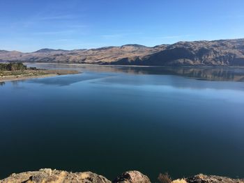 Scenic view of lake and mountains against clear blue sky