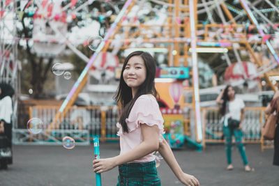 Portrait of young woman standing at amusement park