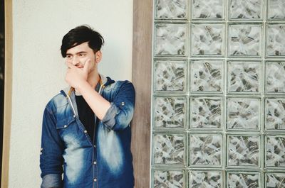 Portrait of young man standing against wall