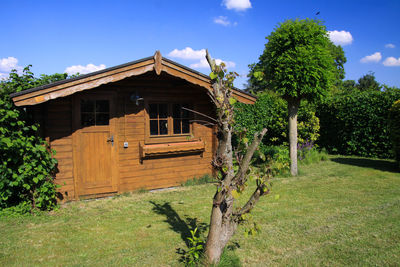 House amidst trees and plants on field against sky