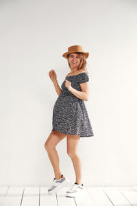 Portrait of young woman standing against white background