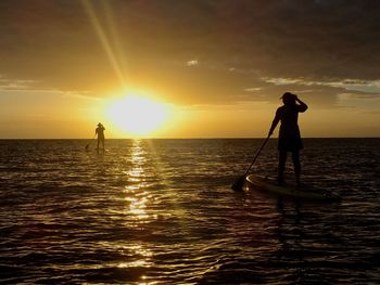 Stand up paddle boarder silhouette, back lit into sunrise 