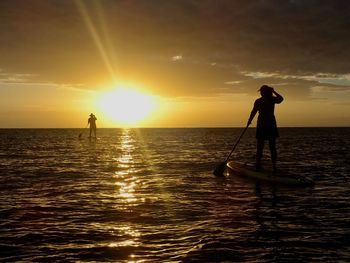 Silhouette man walking on sea against sky during sunset