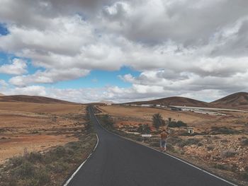 Road leading towards mountains against sky