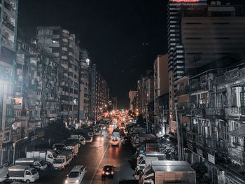 Traffic on city street amidst buildings at night