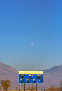 Information sign on landscape against clear blue sky