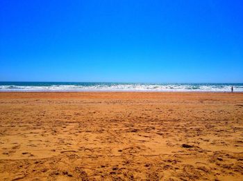 Scenic view of beach against clear blue sky