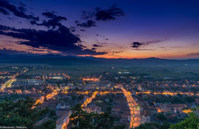 High angle view of illuminated cityscape against sky during sunset