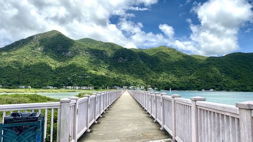 Footbridge over mountain against sky