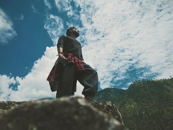 Rear view of man on rock against sky